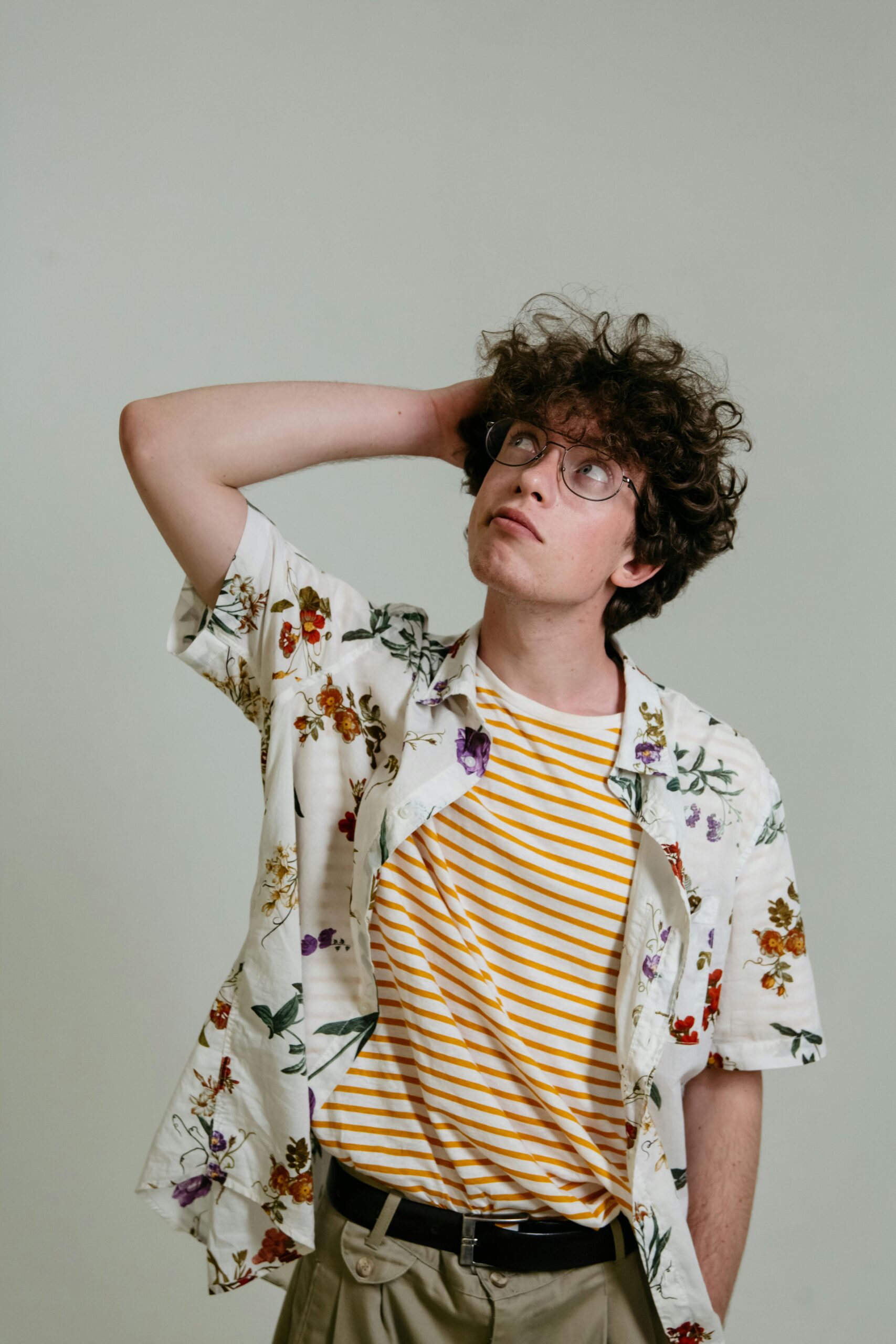 pexels-photo-8638712-8638712 Caucasian man with curly hair and eyeglasses pensively looking up in a studio shot.