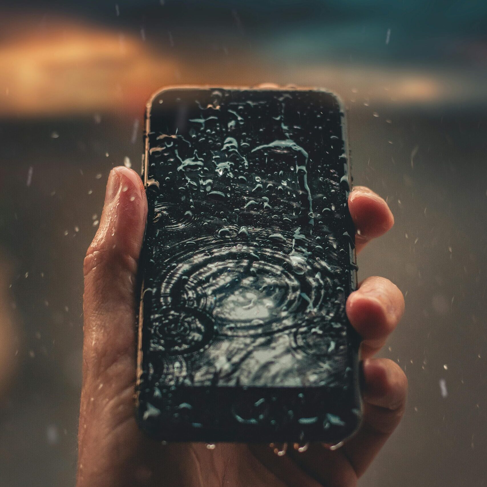 pexels-photo-1826060-1826060 A person holds a smartphone with raindrops on screen, emphasizing water resistance.